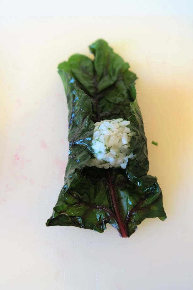 Folding the two long sides of the leaf to partially cover the rice ball