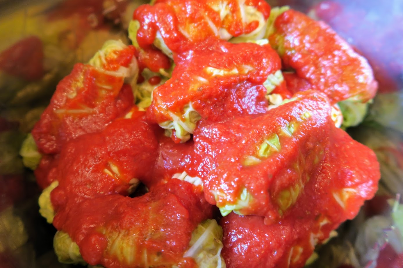 Uncooked cabbage rolls with an even distribution of tomato sauce on top