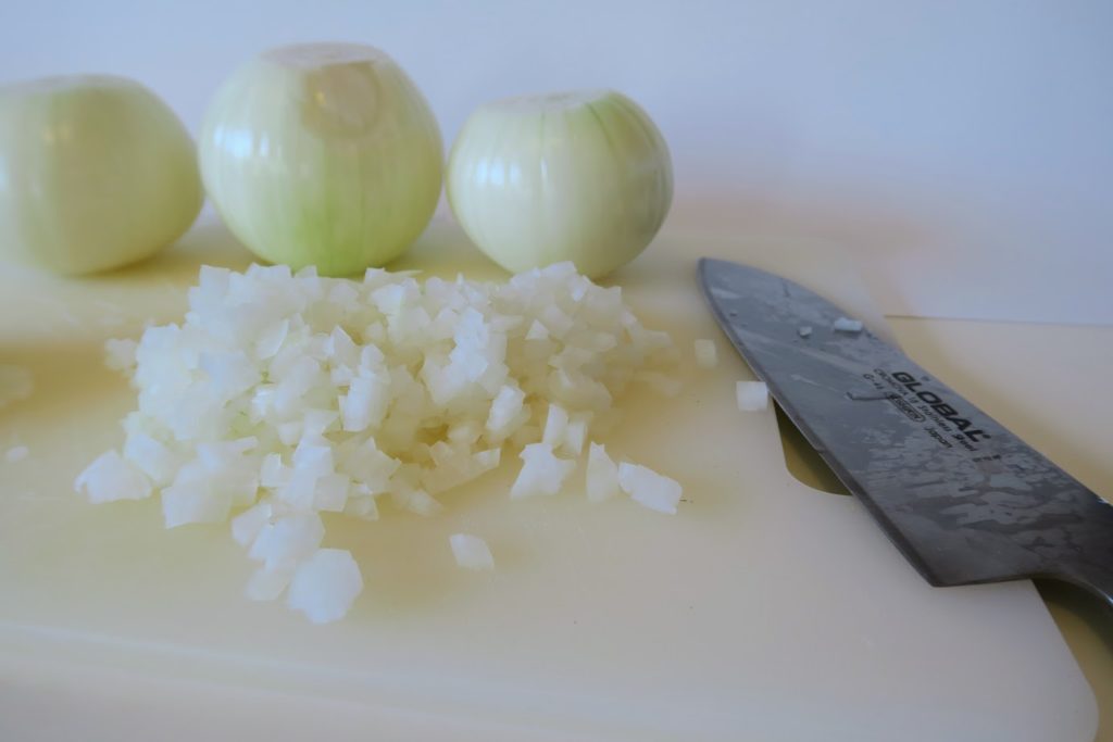 Onions chopped to about an eighth of an inch dice. Two innocent whole onions await their fate.