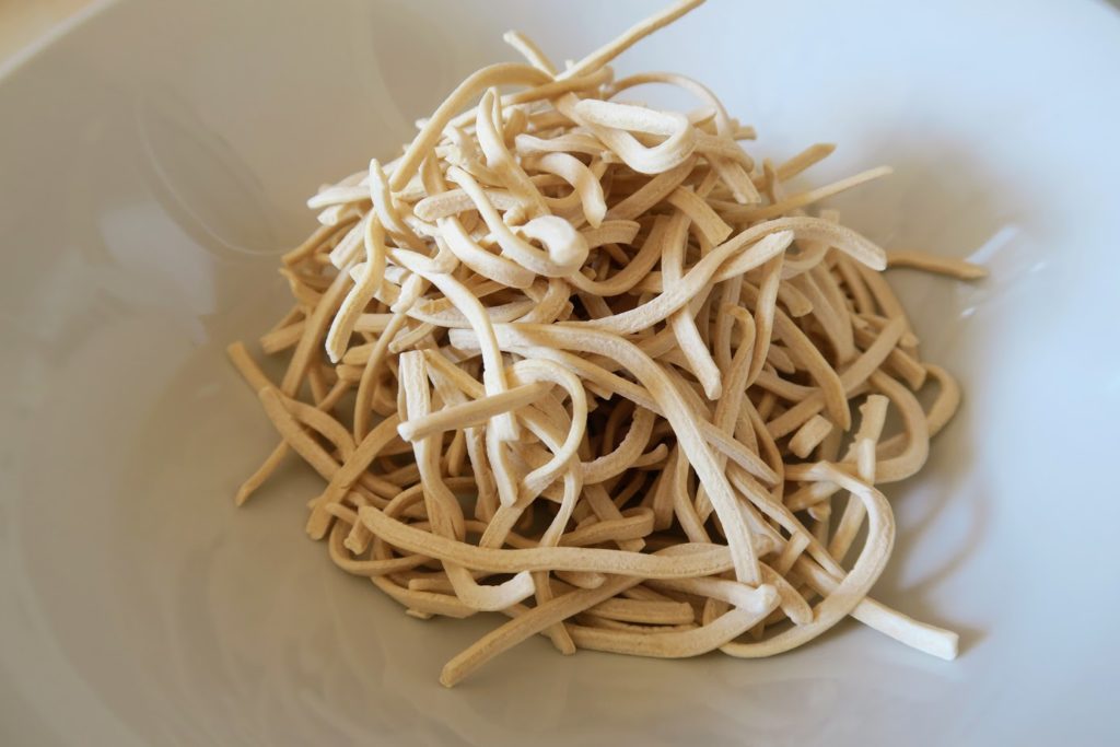 Thicker egg noodles, uncooked in a bowl