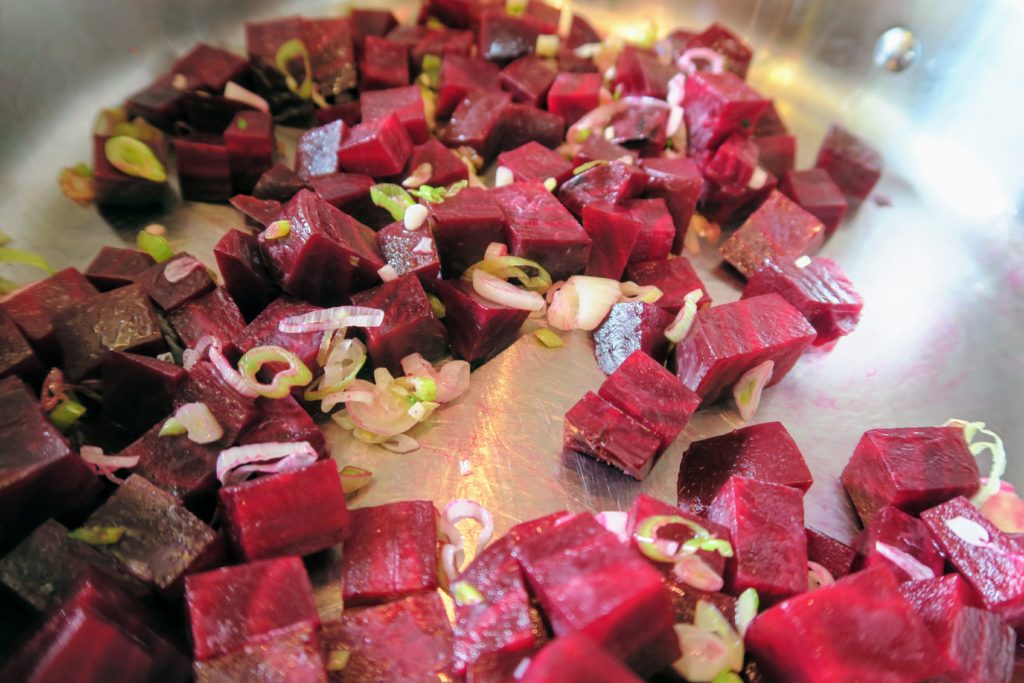 Beet cubes and spring garlic in a frying pan