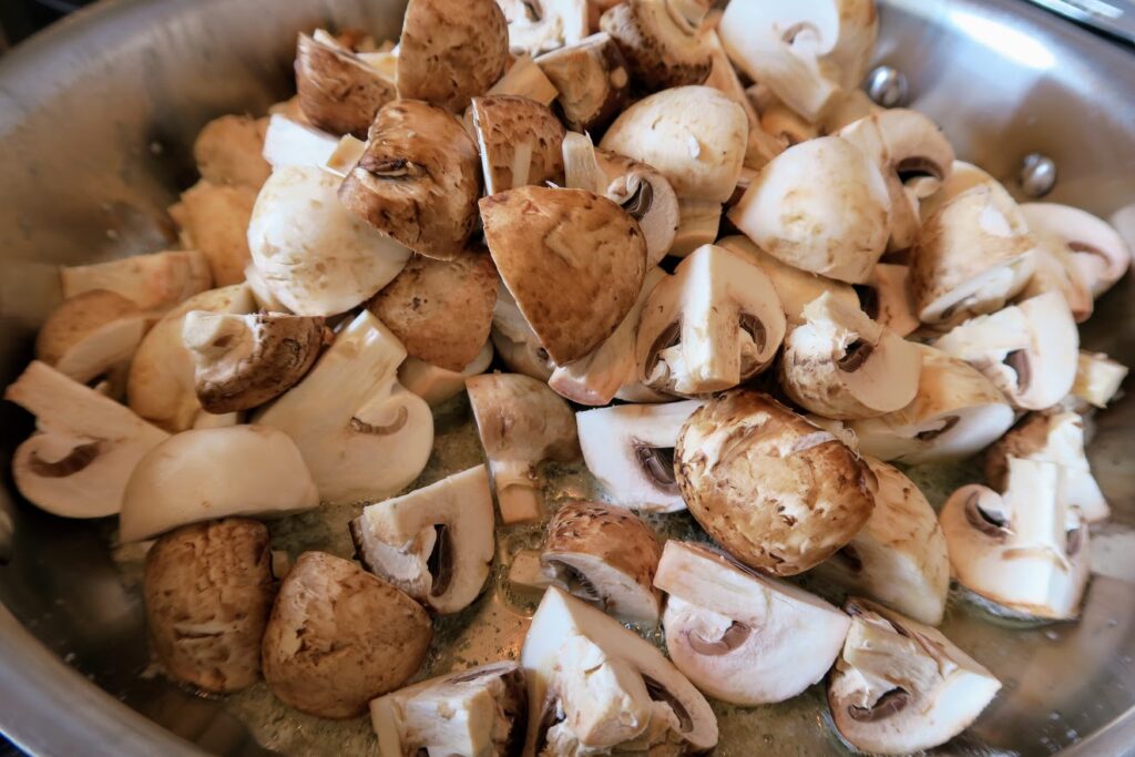 Button mushrooms frying in a pan with butter