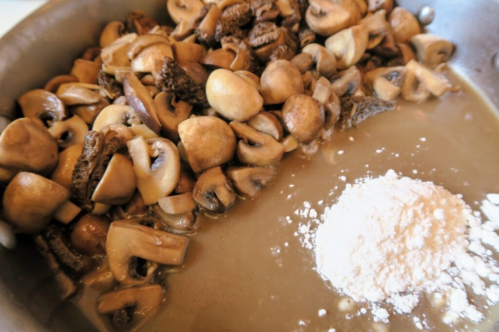Flour added to the pan with mushrooms pushed over to one side
