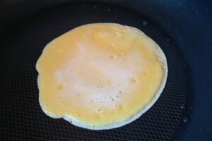 Crepe in a frying pan with bubbles appearing