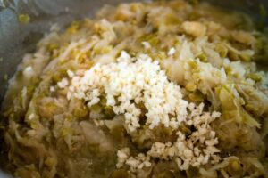 Adding minced garlic to the cooked sauerkraut and peas